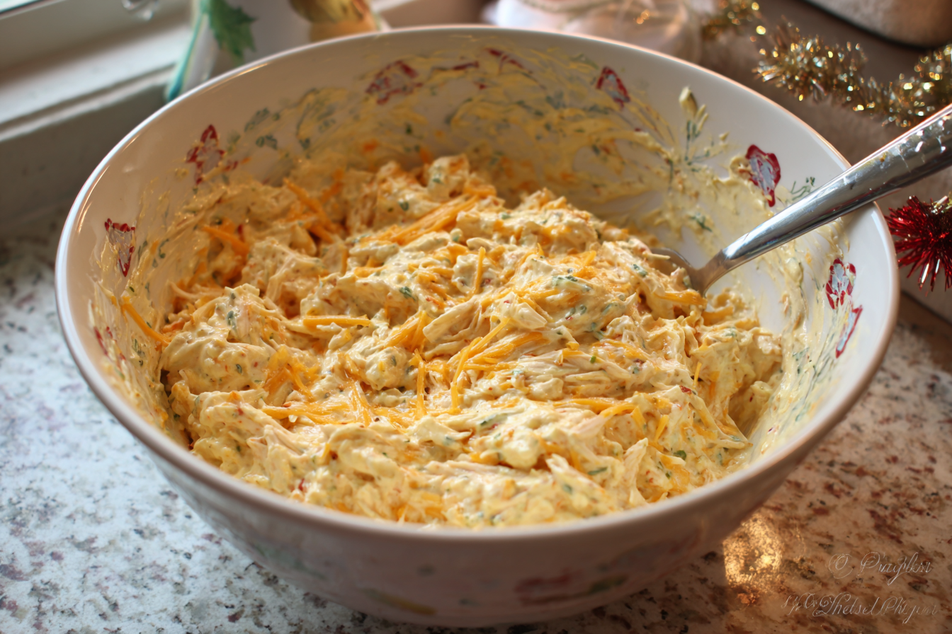 A bowl of creamy ranch mixture with chicken, cheese, corn, and peppers.